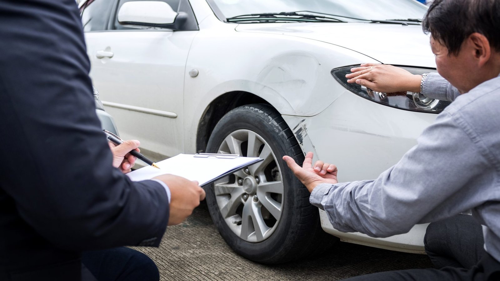 Man agent Filling Insurance Form Near Damaged and examining Car, storm damage claims